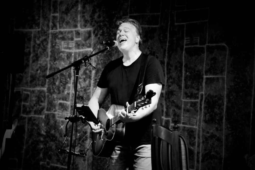 Zwart-wit foto van Pieter Cooreman die zingt tijdens een optreden.